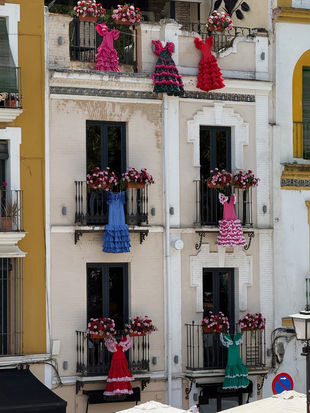 Robes de flamenca suspendues aux balcons fleuris d'une façade sévillane